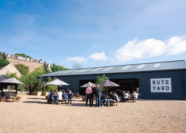 People sitting outside on tables at Bute Yard enjoying artisan local products