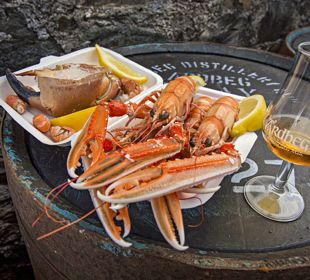 A plate of fresh seafood sitting next to a glass of whisky