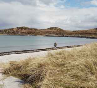 A person wandering along an empty beach on the isle of Gigha