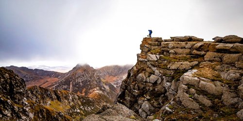 A climber and his dog at a peak with views across a range of peaks