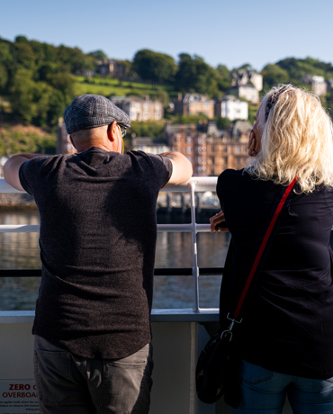 Two people standing looking over the ferry railings to the mainland