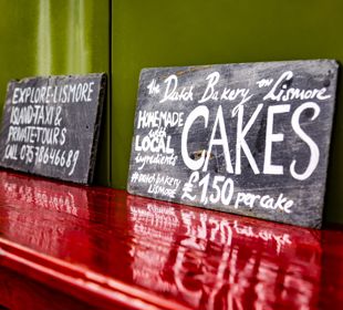 A homemade, chalk board sign for a local bakery selling cakes, Lismore.