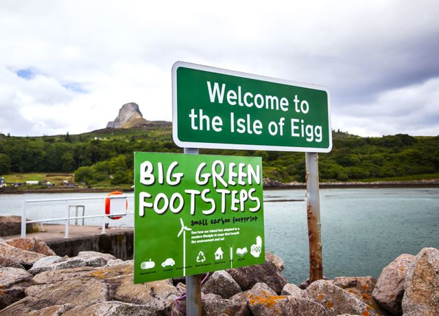 A welcome to Eigg sign with the rocky Sgurr of Eigg in the background