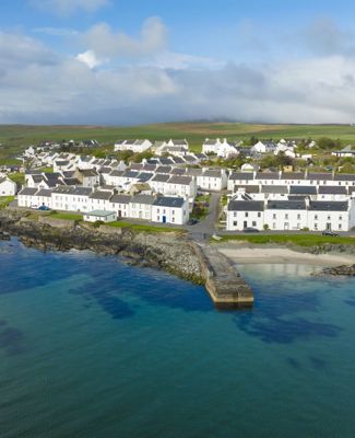 Aerial drone view of the white coloured houses of Port Charlotte and the island coastline