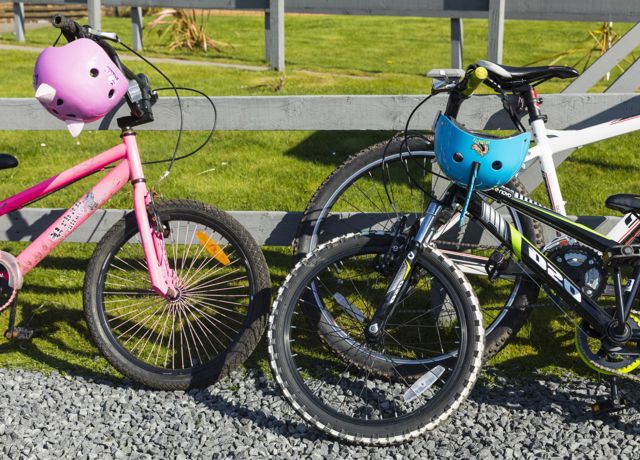 Children's bicycles, leaning against a fence