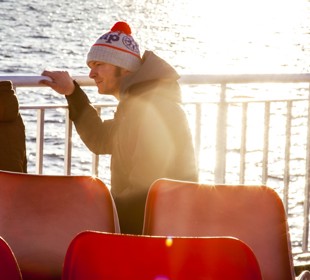 little boy and his dad looking out to sea from the boat deck with the sunset in the background