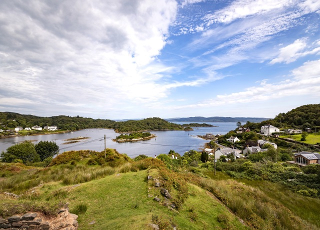 A hilltop view looking towards white houses and across the water