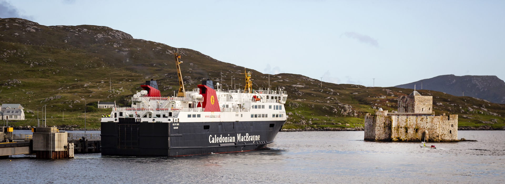 The Caledonian MacBrayne ferry to Barra sitting in the bay next to the rugged stone Kisimul Castle.