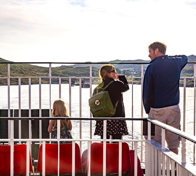 Father and his daughters standing on deck looking out to sea